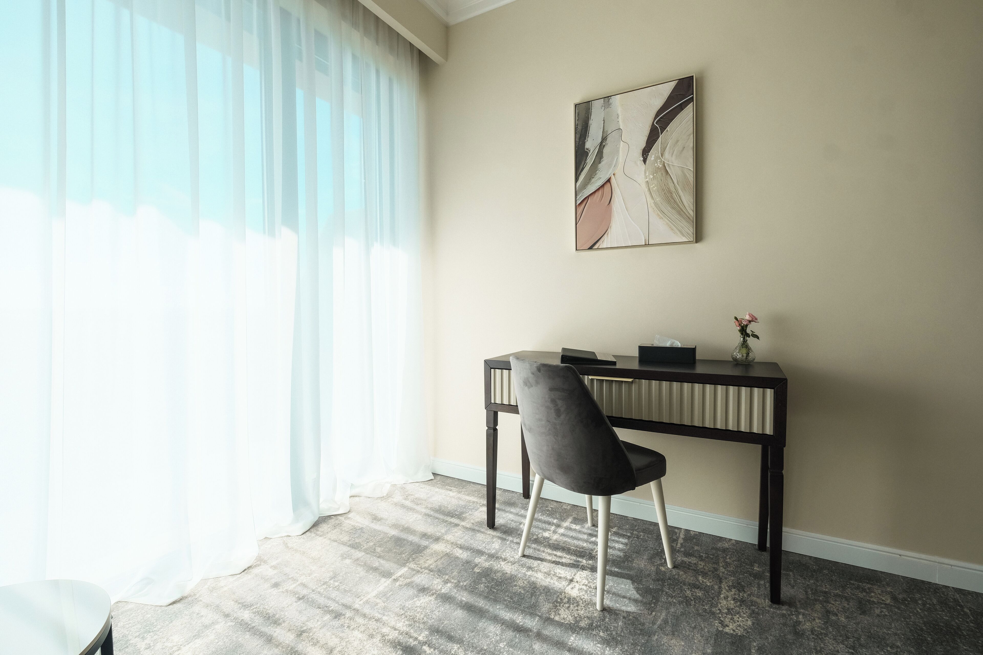 A room with a desk, chair, and a painting on the wall.
