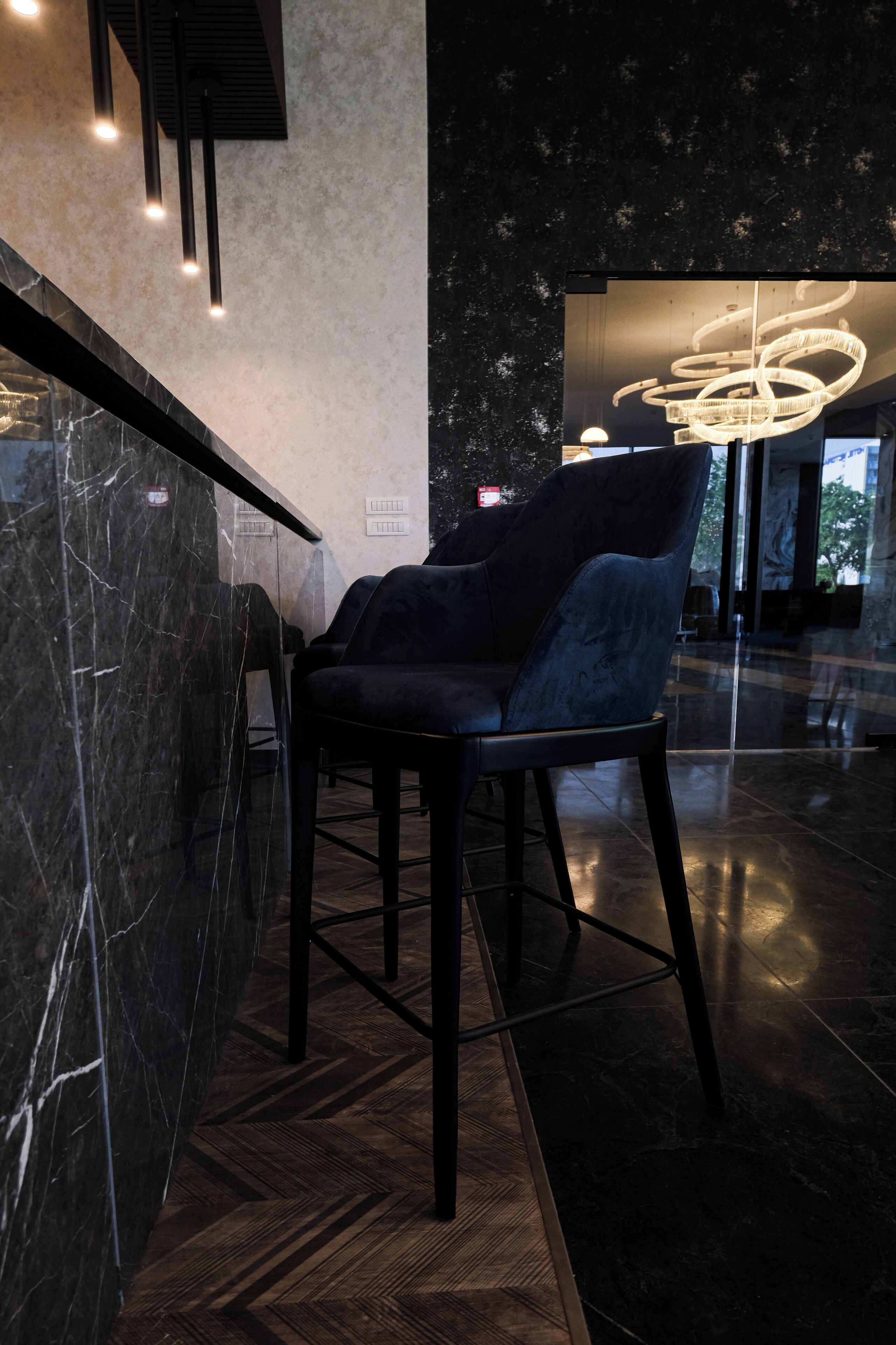 Un interior moderno con una pared de mármol, una silla negra y una lámpara de diseño único.