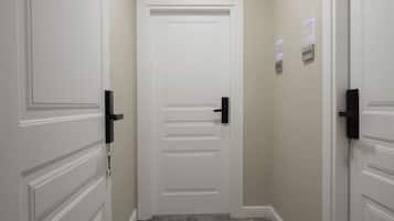 A hallway with white doors, a doorbell, and a wall-mounted intercom system.
