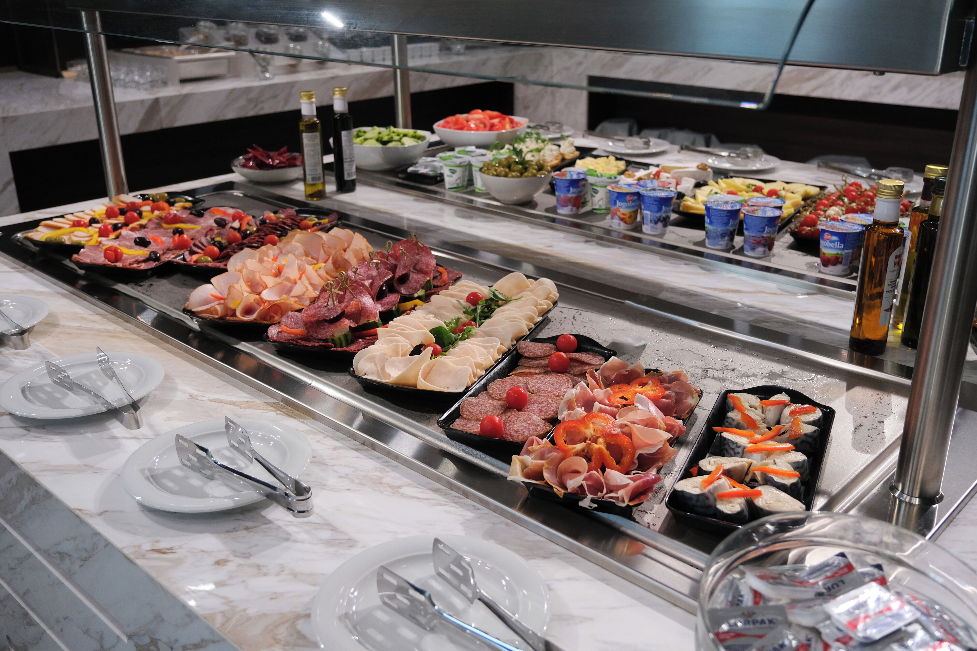 Ein Buffet mit verschiedenen Speisen, darunter Fleisch, Käse und Salate.