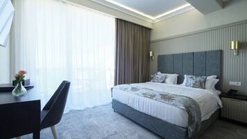 Una habitación de hotel moderna con una cama grande, un escritorio con silla y un florero con flores.
