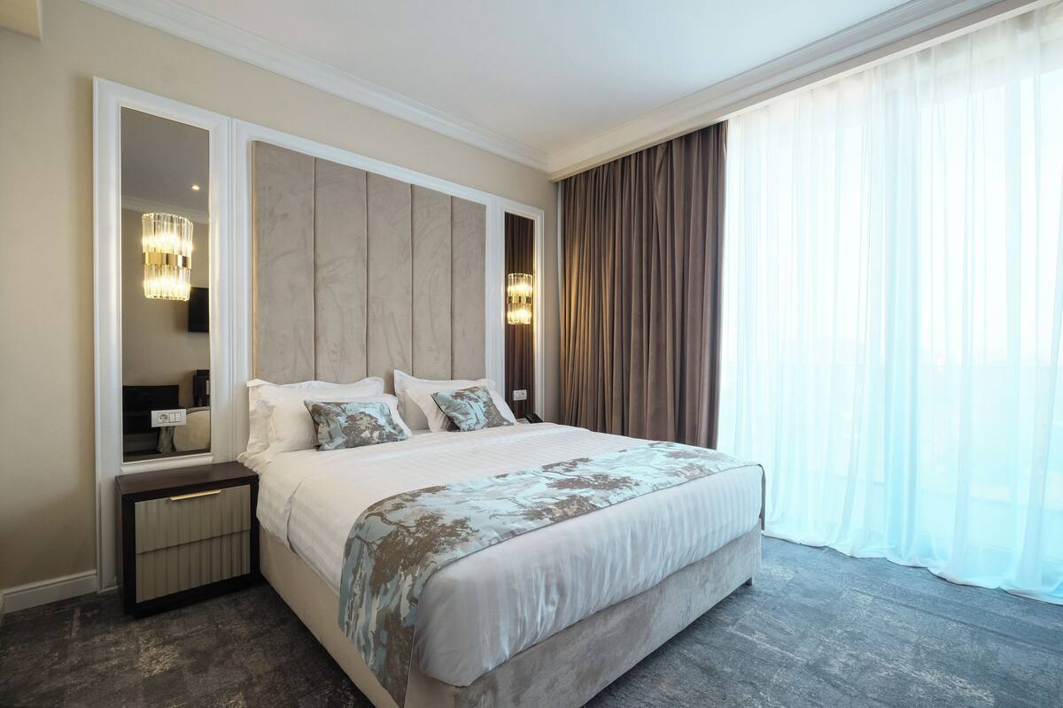 A large bed with a wooden headboard, a bedside table, and a mirror.