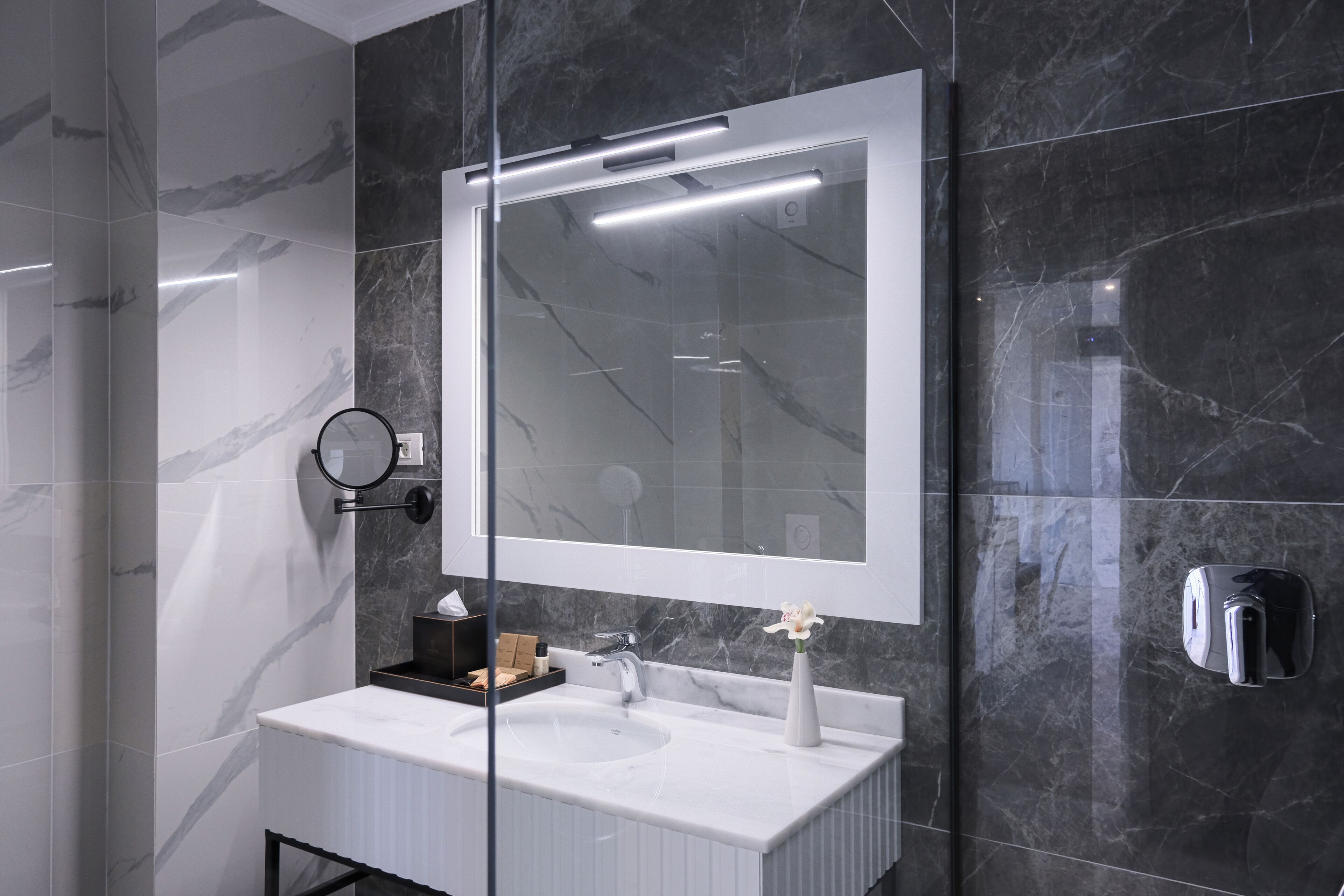 A modern bathroom with a large mirror, two sinks, and a towel rack.