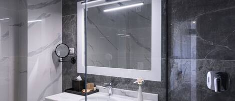 A modern bathroom with a large mirror, two sinks, and a towel rack.