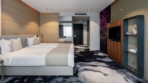 A modern hotel room with a large bed, a flat-screen TV, a wardrobe, and a carpeted floor. - River Park Hotel (Cluj-Napoca)