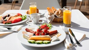 A breakfast table with plates of food, a glass of orange juice, and a cup. - River Park Hotel (Cluj-Napoca)