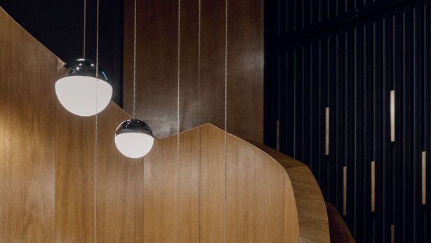 A curved wooden structure with hanging pendant lights. - River Park Hotel (Cluj-Napoca)