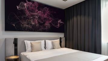 A modern hotel room with a large bed, a headboard with controls, a bedside table, and a large abstract painting on the wall.