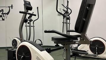 Ett gym med motionscyklar, en roddmaskin och en viktbänk.