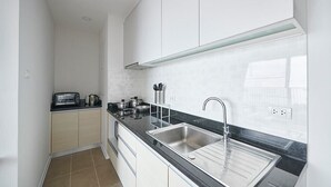 Cocina compacta con tostadora, hervidor y ollas en la encimera, un lavamanos y una ventana con vistas.