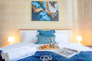 A neatly made bed with a blue blanket, a tray with croissants, a magazine, and a towel. - Zest Gozitan Villa & Pool (Qala)