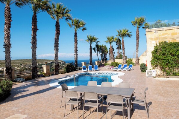 Relax by the pool surrounded by comfortable seating and lush greenery.