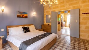 Un dormitorio con cama, mesitas de noche, candelabro, un cuadro y un espejo.