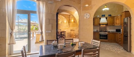A dining area with a table, chairs, and a view through a glass door.