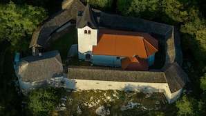 An aerial view of a historic building with a central tower, a courtyard, and surrounding walls.