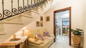 A living room with a sofa, a table with a candle, and a staircase. - Sunny Maltese Townhouse Madonnina Kalkara (Kalkara)
