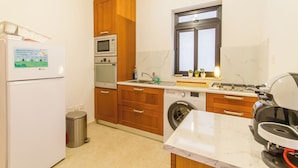 A compact kitchen with a refrigerator, microwave, oven, sink, and a washing machine.