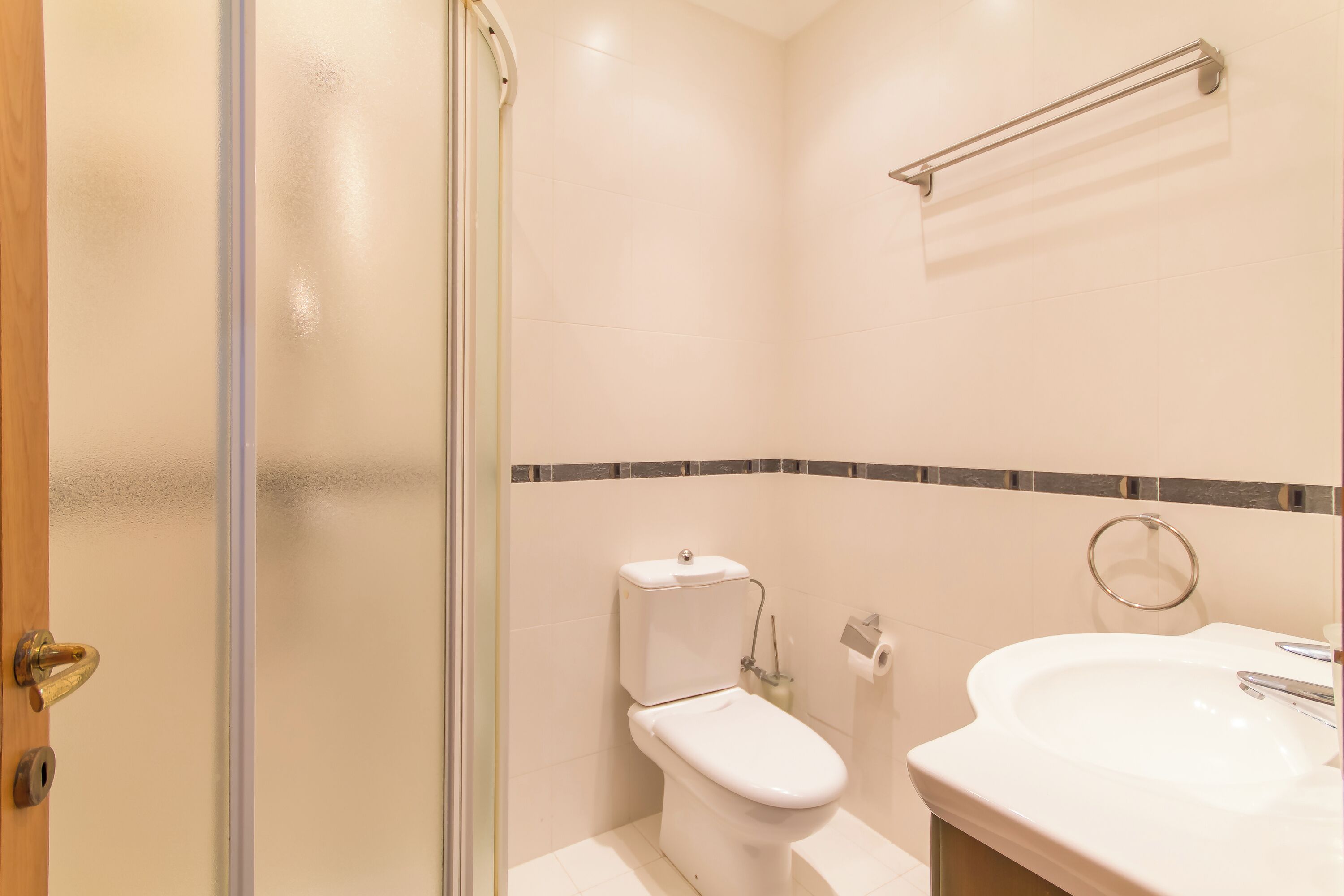 Une salle de bain équipée de toilettes, d’un lavabo et d’une porte de douche en verre.