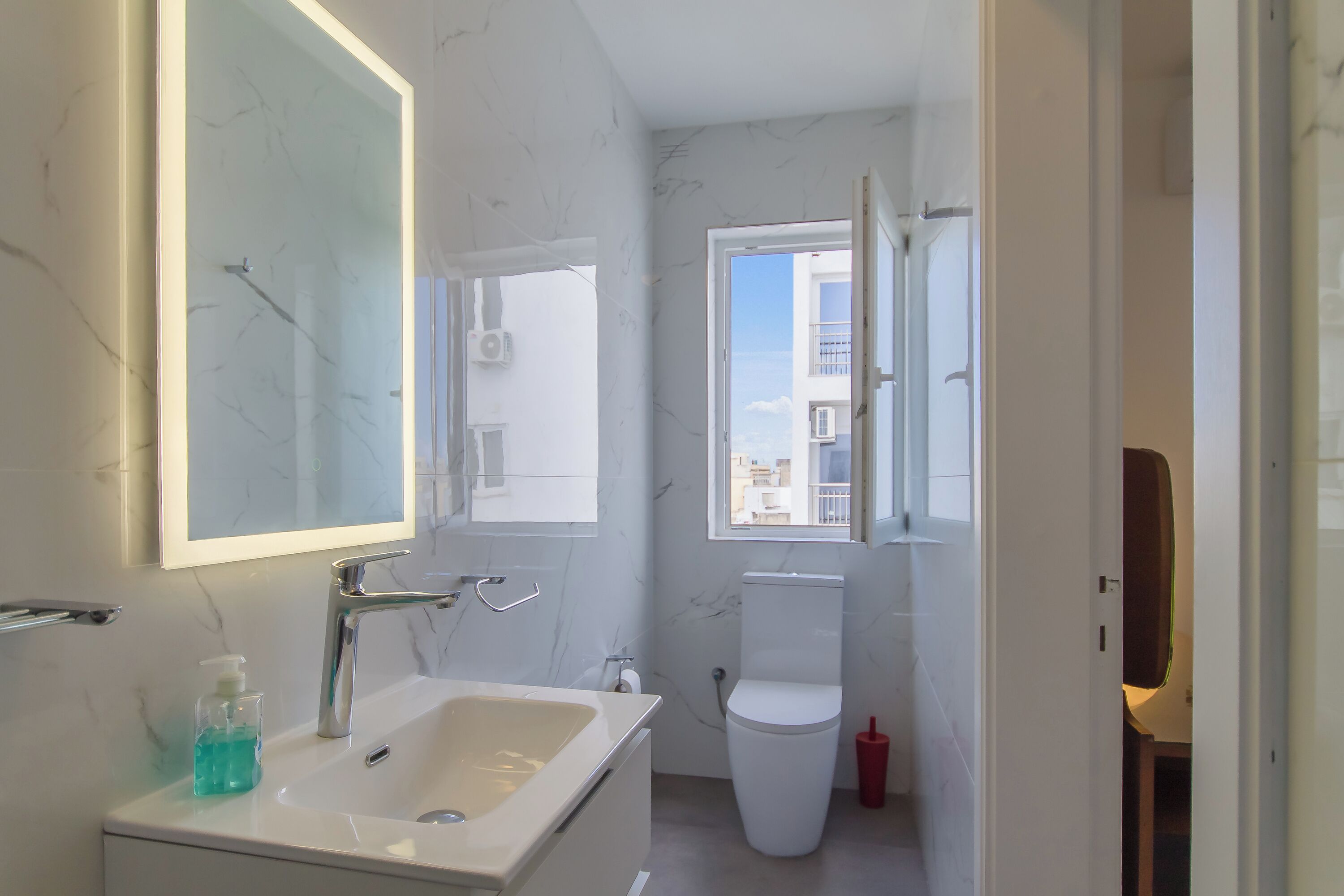 A modern bathroom with a large mirror, a sink, and a toilet.