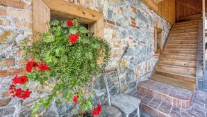 A rustic stone wall with a wooden window and a wooden staircase.