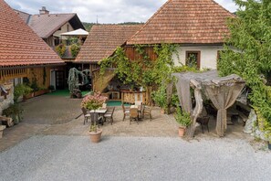 A courtyard with rustic buildings, outdoor seating, and potted plants.