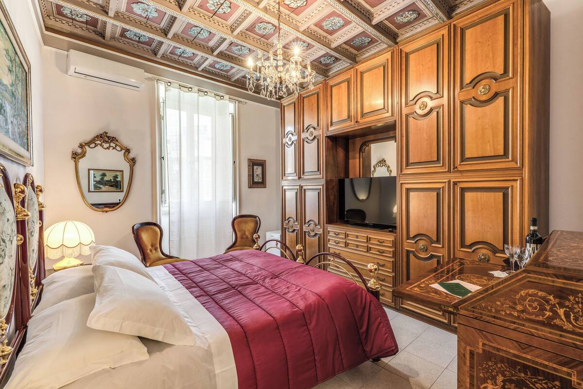 A bedroom with a bed, wooden wardrobe, and a television.