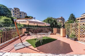 A patio with a table and chairs, a lawn, and a fence. - Villa Alberici (Rome)