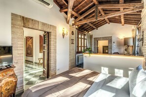 A bedroom with a wooden ceiling, a bed, a dresser, and a television. - Villa Alberici (Rome)