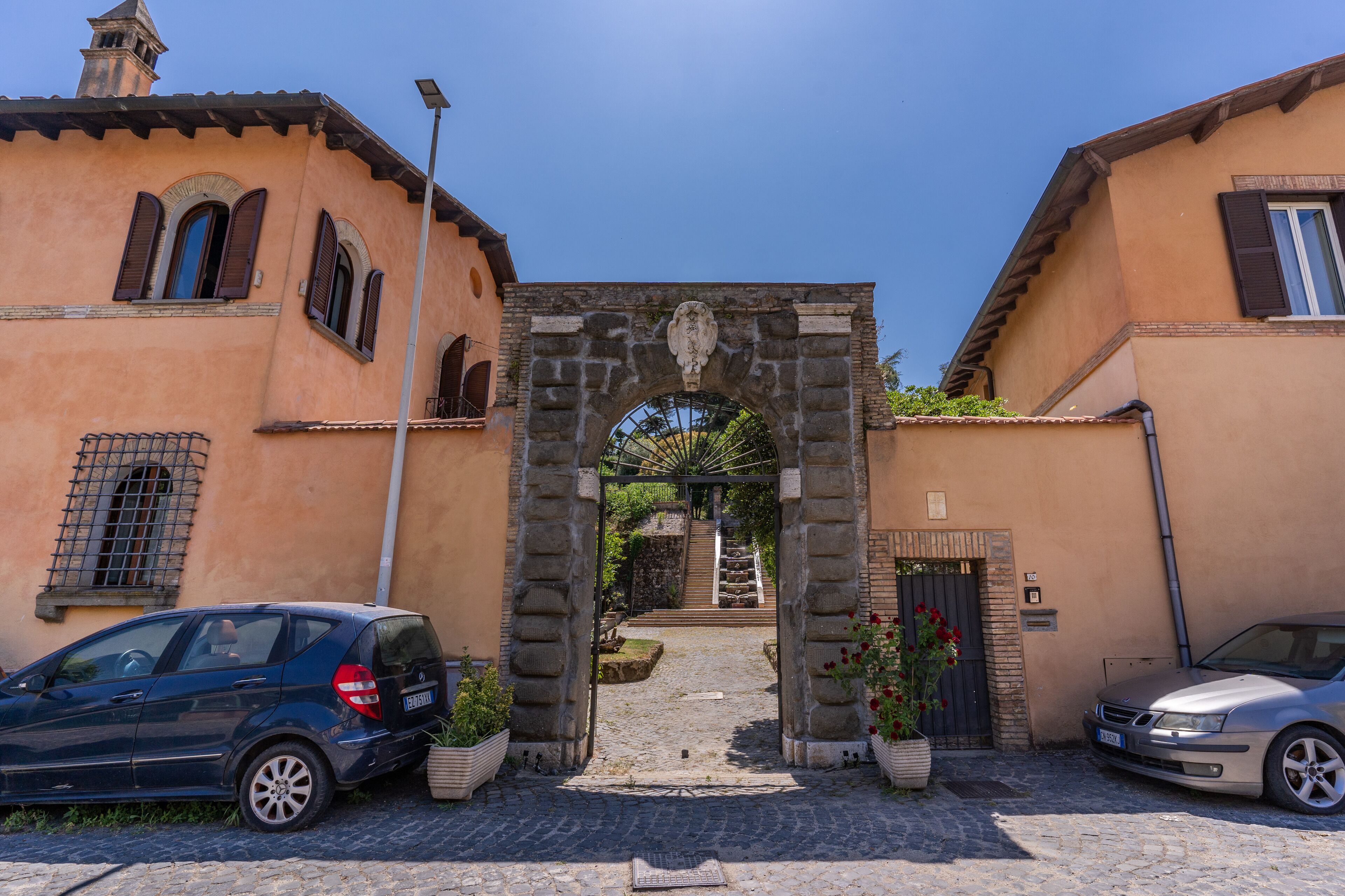 A cobblestone street with a stone archway leading to a building with a tiled roof.