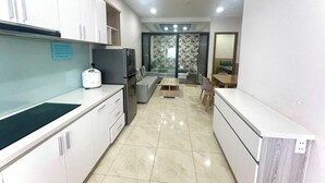Una cocina moderna con armarios blancos, refrigerador empotrado y un comedor con mesa y sillas.