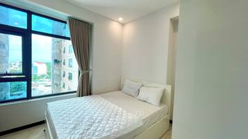 A modern hotel room with a large window, a bed with white bedding, and a view of the cityscape.
