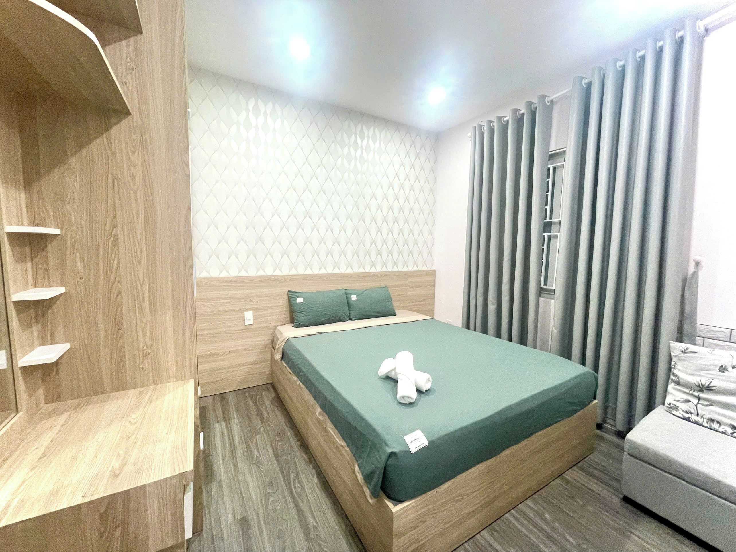 Habitación de hotel ordenada con una cama, un armario de madera y una ventana con cortinas.