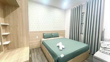 Habitación de hotel ordenada con una cama, un armario de madera y una ventana con cortinas.