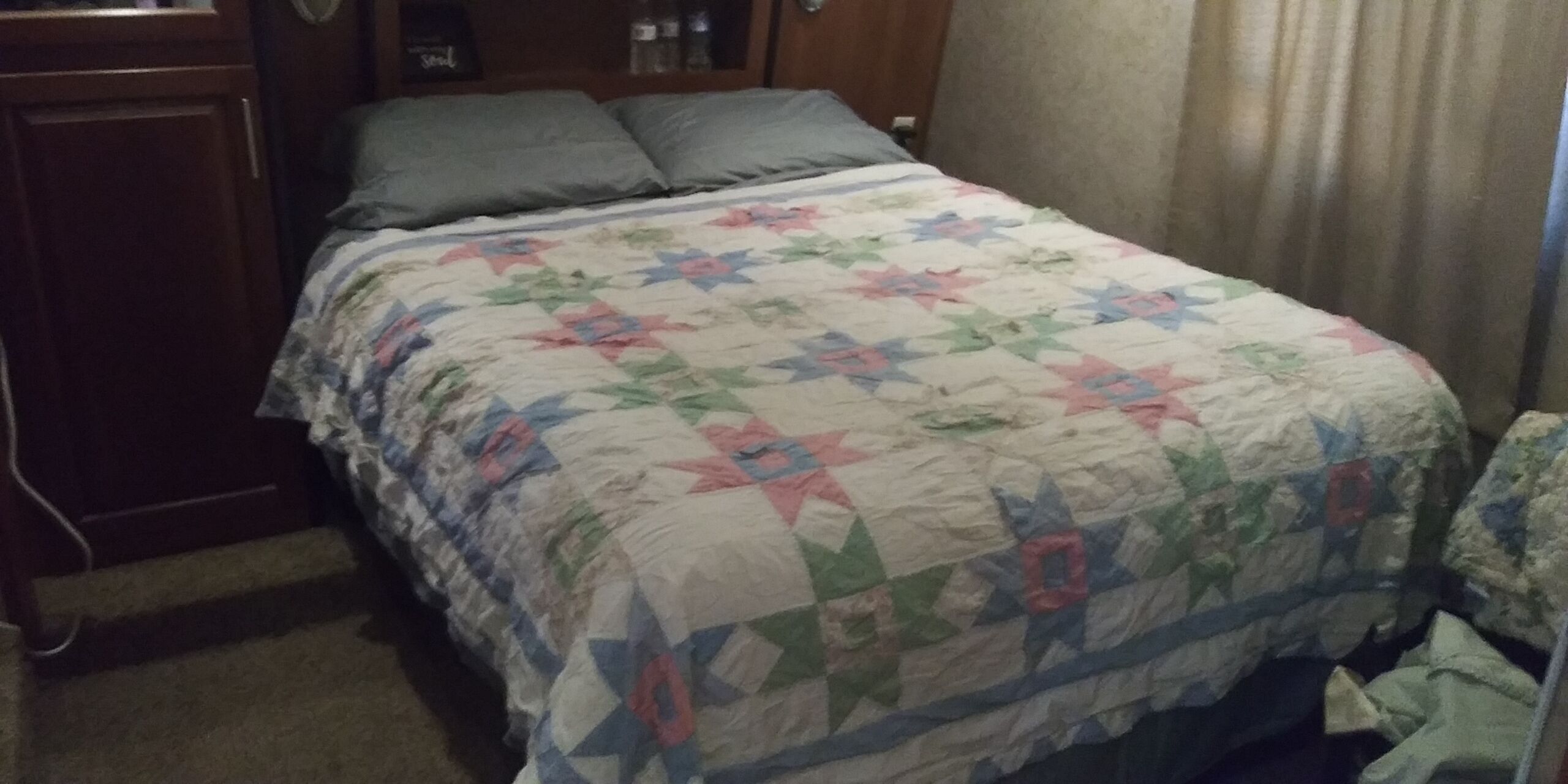A bedroom with a bed, a wooden wardrobe, and a curtain.