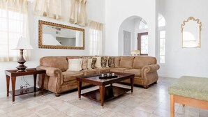 Ein Wohnzimmer mit braunem Sofa, einem Holztisch, einer Lampe und einem Spiegel an der Wand.