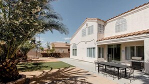 Ein zweistöckiges Haus mit Terrasse, Grill und Essbereich.