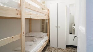 Ein Schlafraum mit Etagenbetten, einem Kleiderschrank und einem Spiegel.