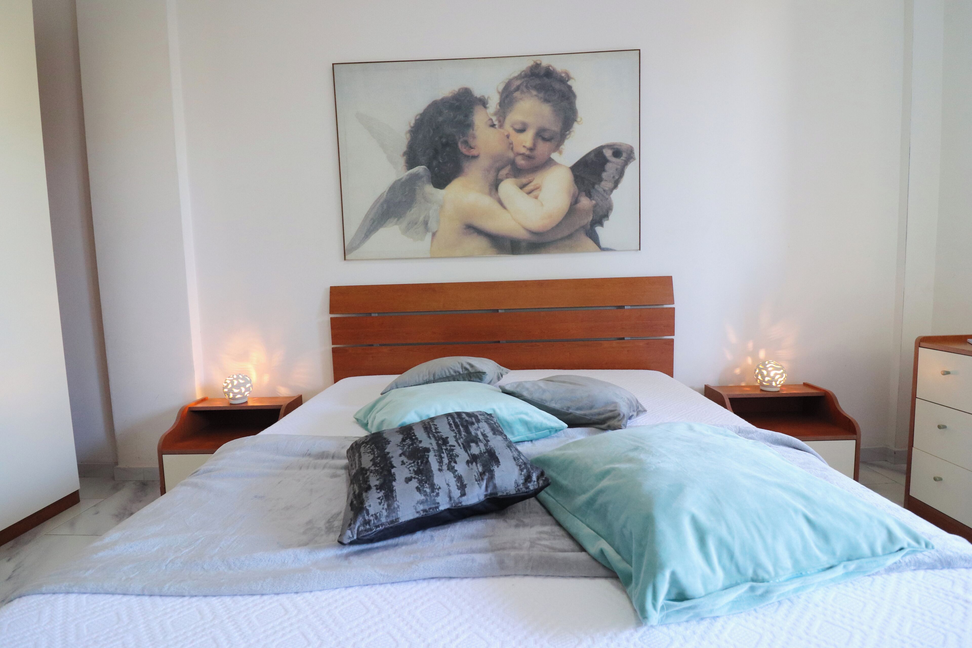 A neatly made bed with pillows and a framed artwork above it.