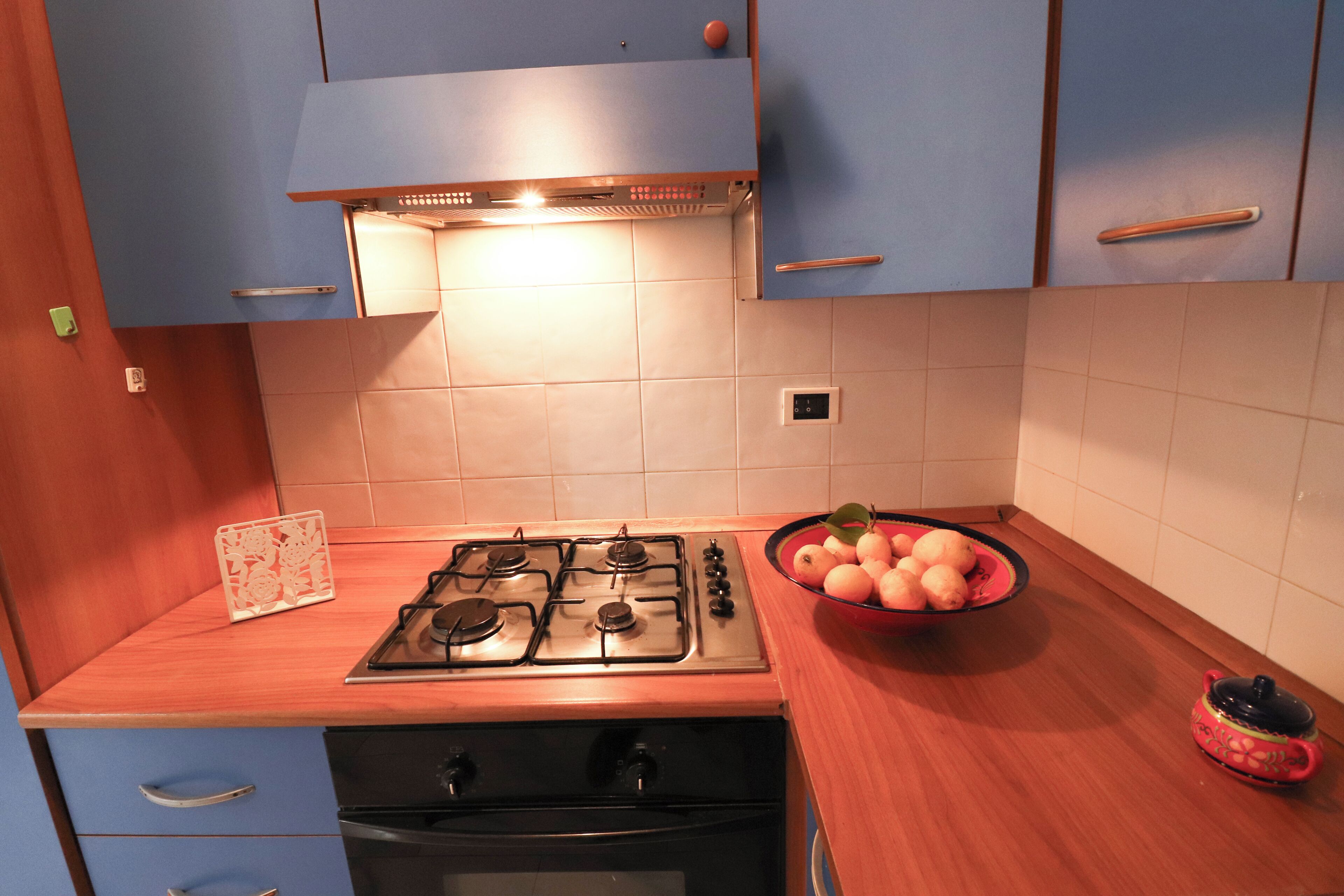 Una cocina con estufa a gas, horno y un tazón de fruta en la encimera.