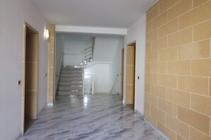 A hallway with a marble floor, a staircase, and a brick wall.