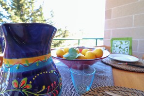 A table with a decorative vase, a bowl of fruit, and a glass.