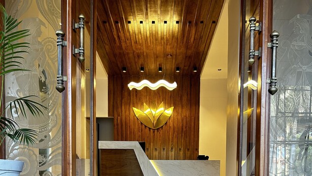 Un espace d’accueil doté d’un plafond en bois, d’un comptoir de réception en marbre et d’un luminaire moderne.