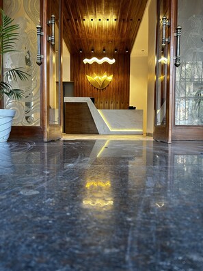 A reception area with a wooden ceiling, a marble reception desk, and a modern light fixture.