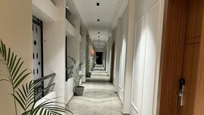 Un couloir doté d’un sol en marbre, de plantes en pot et d’une porte en bois.