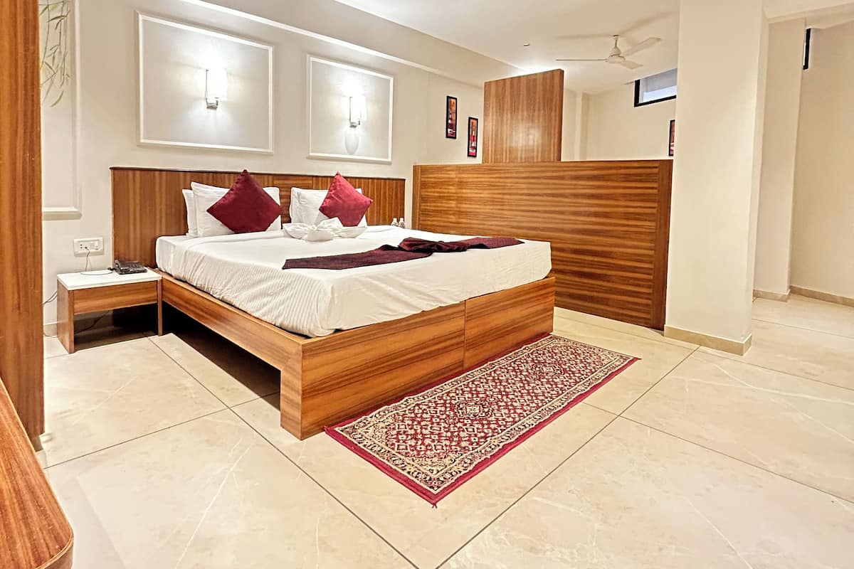 A modern bedroom with a wooden bed, a nightstand, a red patterned rug, and two ceiling fans.