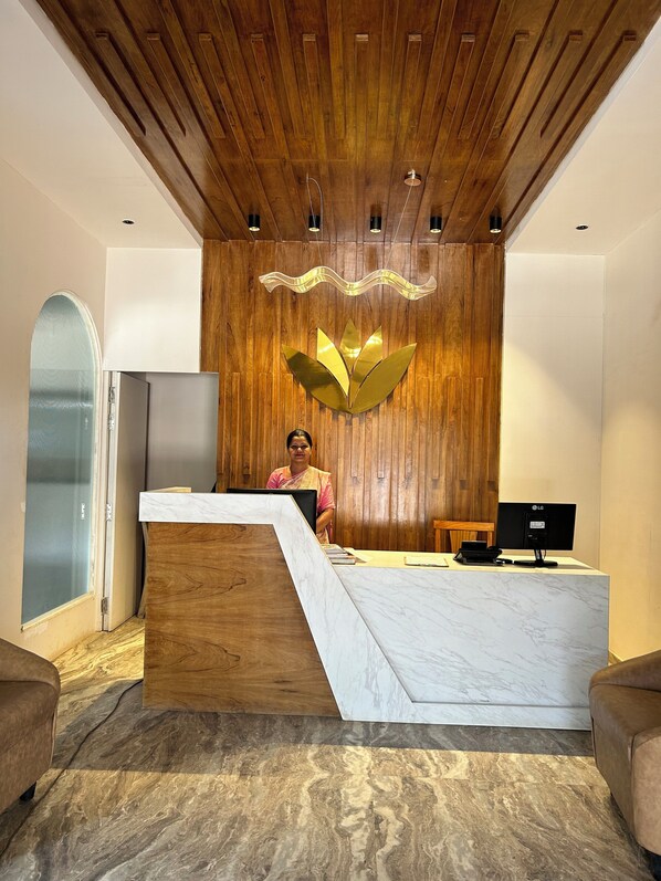 A reception desk with a wooden backdrop and a marble counter.