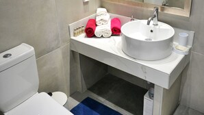 A modern bathroom with a white toilet, a large mirror, and a white sink.