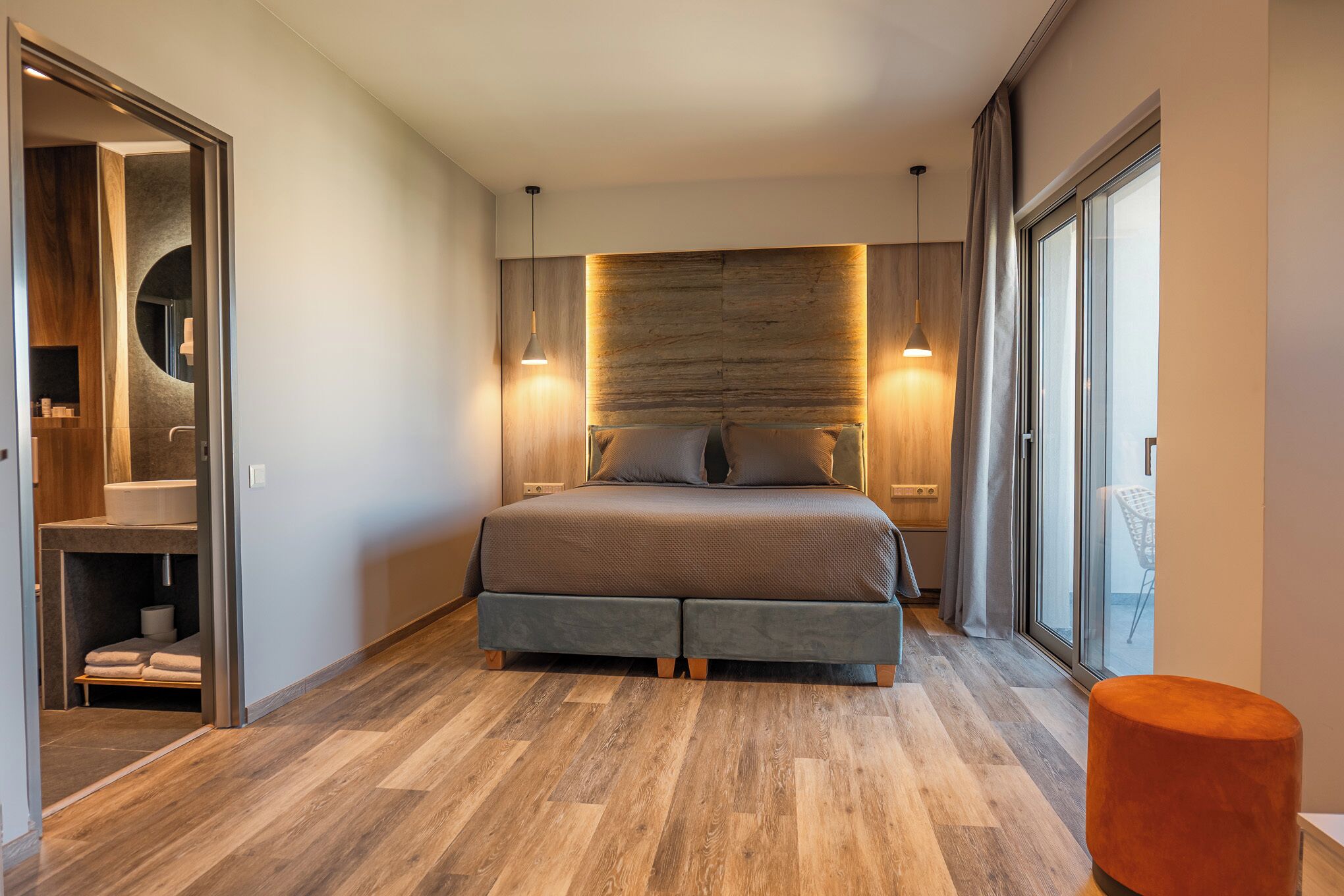 Un dormitorio moderno con una cama grande, cabecera de madera y zona de ducha con mampara de vidrio.