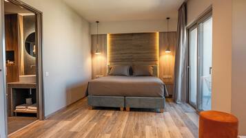 Un dormitorio moderno con una cama grande, cabecera de madera y zona de ducha con mampara de vidrio.