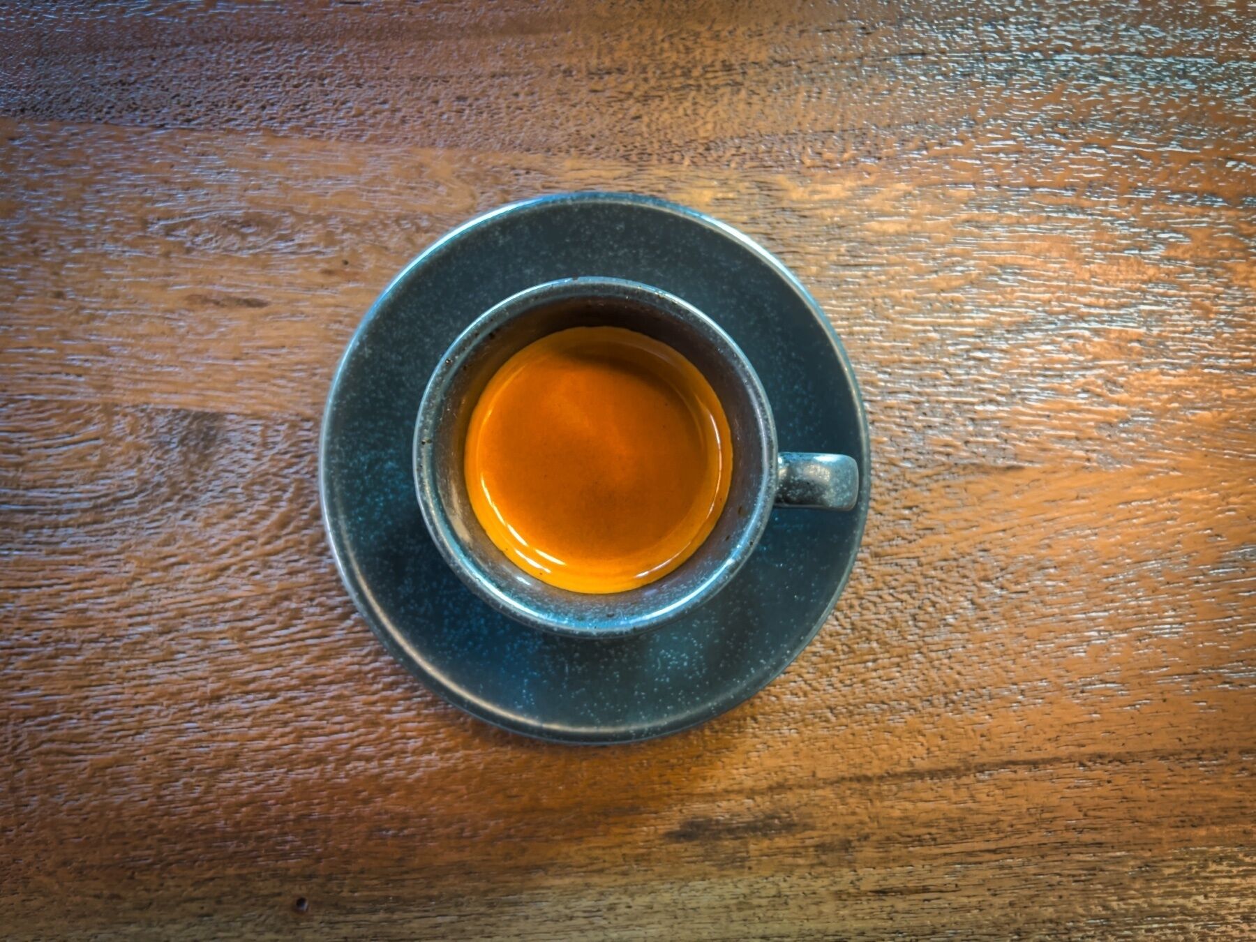 A cup of tea on a saucer on a wooden table.